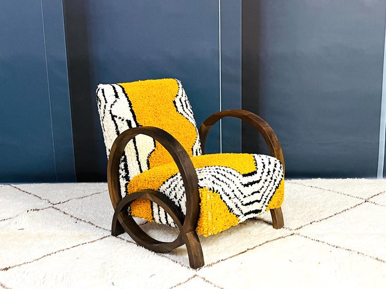 May include: A yellow and white patterned armchair with a dark wood frame. The chair has a unique curved design and is sitting on a white rug.