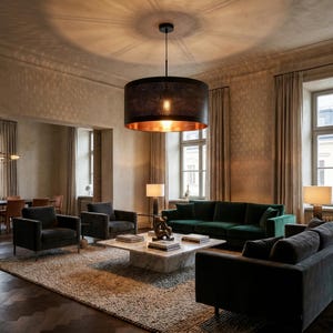 May include: A modern living room featuring a large, black, perforated drum pendant light with a copper interior. The room includes a green sofa, armchairs, a marble coffee table, and a neutral-toned rug, creating a sophisticated ambiance.