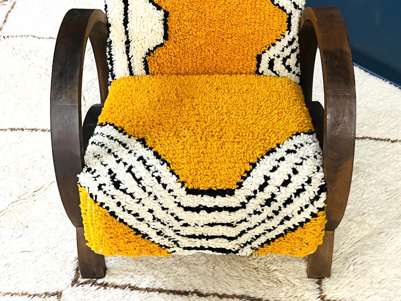 May include: A yellow and white patterned chair with dark brown wooden arms and legs. The chair is upholstered in a thick, fuzzy fabric.