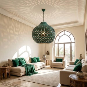 May include: A large, spherical, dark green metal pendant light fitting with an intricate, repeating geometric cutout pattern that casts a starburst shadow on the ceiling, suspended by a chain from the centre of a bright, neutral-toned living room.