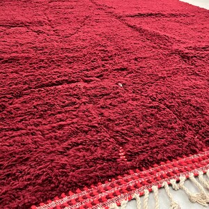 Puede incluir: Una alfombra de pelo rojo intenso con un borde de flecos. La alfombra est&aacute; hecha de fibras suaves y mullidas y tiene una sensaci&oacute;n lujosa.