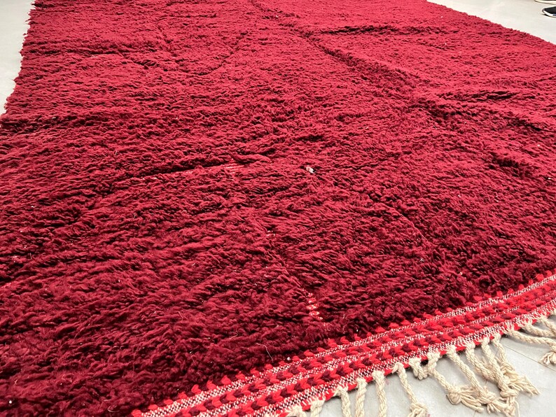 Puede incluir: Una alfombra de pelo rojo intenso con un borde de flecos. La alfombra est&aacute; hecha de fibras suaves y mullidas y tiene una sensaci&oacute;n lujosa.