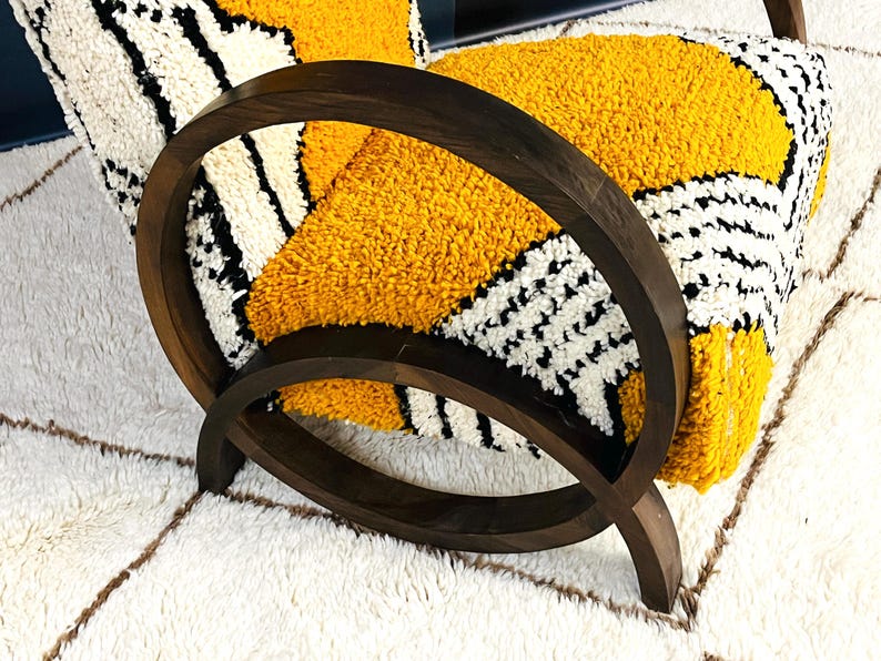 May include: A wooden armchair with a yellow and black patterned cushion. The chair has a unique curved design and is upholstered in a soft, plush fabric.