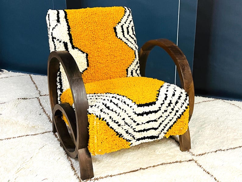 May include: A yellow and white patterned armchair with dark wood arms and a curved wooden base. The chair is sitting on a white rug.