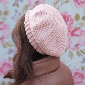 May include: A pink crocheted beret hat. The hat is made with a textured stitch and has a simple, classic design.