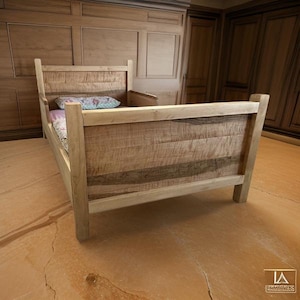 May include: A wooden bed frame with a headboard and footboard made of light-colored wood. The bed has a simple design with a mattress and a patterned pillow. The bed is in a room with wooden paneling and flooring.