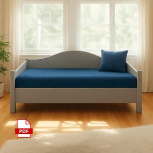 May include: A gray daybed with a navy blue mattress and a matching pillow. The daybed has a curved headboard and footboard. The room has large windows and hardwood floors.