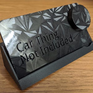 May include: Black plastic desk organizer with geometric pattern and the text "Car Thing Not Included". The organizer has a stand and a circular piece attached to the top.