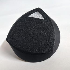 May include: A black, triangular-shaped knob with a silver triangle on top.