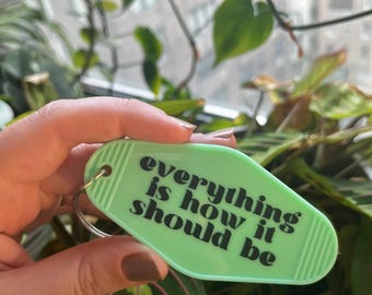May include: A light green motel key chain with the text "everything is how it should be" in black lettering.