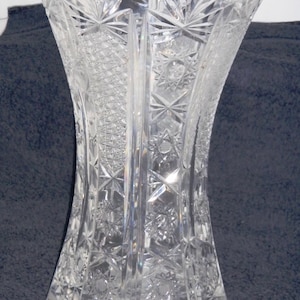 May include: A clear glass vase with a cut glass design. The vase has a wide mouth and a narrow base.