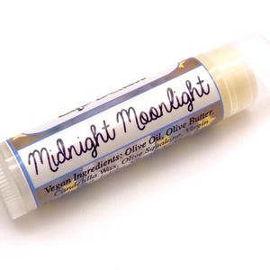 May include: A lip balm tube with the words "Midnight Moonlight" in a script font. The label also lists vegan ingredients like olive oil and olive butter. The tube is white with a clear cap.