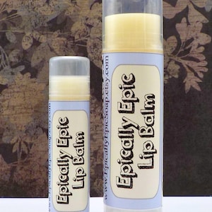 May include: Two cylindrical lip balm tubes of different sizes with clear plastic caps. The labels are light blue with cream-colored rectangular centers featuring the black text Epically Epic Lip Balm and the URL www.EpicallyEpicSoap.etsy.com.
