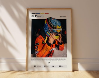 Puede incluir: Póster enmarcado con O. Piastri con traje y casco de carreras. El casco es azul, amarillo y naranja. El póster incluye el logotipo de McLaren y texto. El póster está en un marco de madera y se muestra contra una pared blanca.