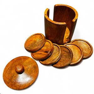 May include: A set of six round wooden coasters with a matching wooden storage container. The coasters are stacked on top of each other and the container has a lid.