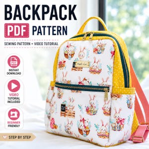Op de afbeelding: Een witte rugzak met een patroon van konijntjes en paaseieren. De rugzak heeft gele stippenaccenten, een gele handgreep en een roze band. Tekst op de afbeelding luidt "BACKPACK PDF PATTERN" en "SEWING PATTERN + VIDEO TUTORIAL".