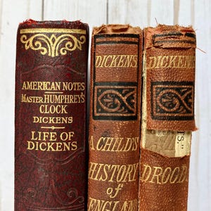 Pila di libri antichi rossi di Charles Dickens: libri decorativi degli anni 1880-1930