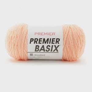 May include: A ball of Premier Basix worsted weight yarn in a pale peach hue. The label displays "Premier Basix" in black, with "Worsted" and other details. The yarn is 328 meters in length.