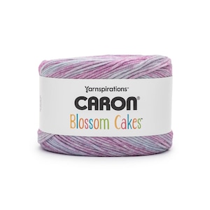 May include: A skein of Caron Blossom Cakes yarn. The yarn is a blend of pink, lavender, and gray. The label reads "Yarnspirations" and "Caron Blossom Cakes" in a colorful font.