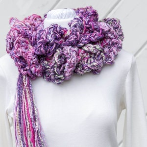 Hand crochet chunky ruffled mixed berry scarf with multiple strands of varied synthetic yarns in shades of purple grape, blueberry and raspberry. This purple scarf is 93 inches long by 6 inches wide. Soft and warm with 15 inch long tassel for tying.