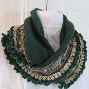 Close view of emerald green infinity scarf wrapped double around neck of mannequin shows details of the narrow vintage ivory lace and vintage mustard yellow and green plaid fabric trim stitched near the kelly green ruffled edge of the scarf.