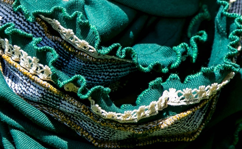 Close up of emerald green scarf shows details of the edges. Narrow vintage ivory lace stitched near kelly green stitched ruffled edge, then vintage plaid fabric trim with green and white vertical stripes and mustard yellow horizontal stripes.