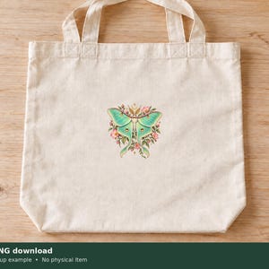 Pu&ograve; includere: Una borsa tote in tela color naturale con un'illustrazione grafica centrata di una falena luna verde chiaro circondata da piccoli fiori rosa e foglie verdi. Il disegno &egrave; posizionato al centro della borsa, dotata di due manici.