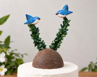 Zwei Schwalben tragen eine Kokosnuss als Hochzeitstortenfigur, handgeschnitzte Holzvögel auf Kokosnuss, verspielte tropische Gartenhochzeitsdekoration