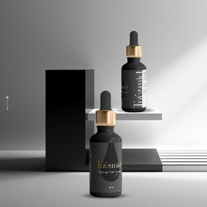 Może przedstawiać: Dwie czarne butelki serum do włos&oacute;w Tricemid Therapy ze złotymi zakraplaczami. Butelki stoją na białej p&oacute;łce i czarnym bloku. Etykieta zawiera nazwę marki i szczeg&oacute;ły produktu. Butelki mają po 30 ml.