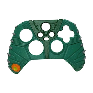 Könnte beinhalten: Grüne Kunststoffschale für einen Gaming-Controller mit strukturierter Oberfläche und einem kleinen orangenen Detail.