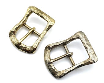 May include: Two gold-toned metal belt buckles with a hammered texture. The buckles are designed with a simple rectangular shape and a center bar.
