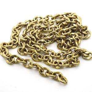 Puede incluir: Una cadena dorada con eslabones ovalados, tendida sobre una superficie blanca. La cadena es de metal y tiene un acabado brillante. Los eslabones están entrelazados, creando un bucle continuo. Esta cadena es adecuada para joyería o fines decorativos.