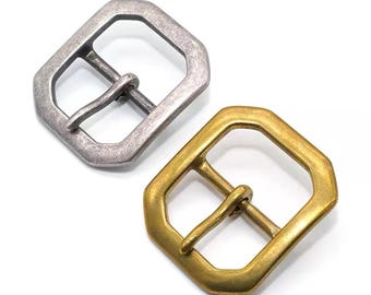 May include: Two metal belt buckles. One is silver-toned with a matte finish, and the other is gold-toned with a shiny finish. Both have a geometric octagonal shape with a central bar for the belt strap.
