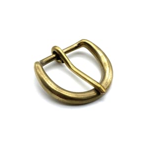 Puede incluir: Una hebilla de latón con un marco redondeado en forma de D y una sola punta. La hebilla es un diseño simple y clásico.