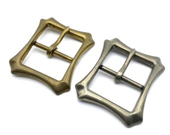 May include: Two metal belt buckles with a square shape and a unique design. One buckle is gold and the other is silver.