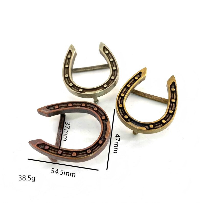 K&ouml;nnte beinhalten: Drei metallene, hufeisenf&ouml;rmige Dekorationsgegenst&auml;nde in Bronze-, Gold- und Silbert&ouml;nen. Das gr&ouml;&szlig;te Hufeisen misst 5,45 cm breit, 4,7 cm hoch und 3,7 cm tief und wiegt 38,5 g. Jedes Hufeisen hat eine Reihe kleiner L&ouml;cher.