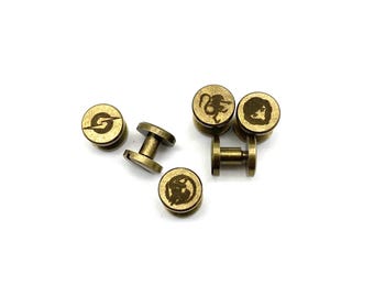 Könnte beinhalten: Ein Satz von sechs goldfarbenen Metall-Schraubknöpfen mit verschiedenen gravierten Designs.
