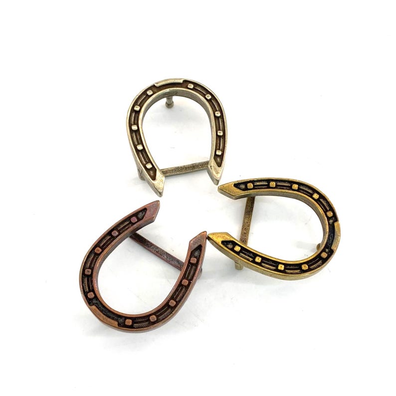 K&ouml;nnte beinhalten: Drei metallene hufeisenf&ouml;rmige Objekte in den Farben Silber, Bronze und Gold. Jedes Hufeisen hat eine Reihe kleiner, gleichm&auml;&szlig;ig verteilter Vertiefungen entlang des &auml;u&szlig;eren Randes. Die Objekte sind auf wei&szlig;em Hintergrund angeordnet.