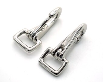 May include: Two shiny, silver-colored swivel snap hooks. Each hook has a rectangular loop on one end and a spring-loaded clasp on the other. The hooks are made of a polished metal and are set against a white background.