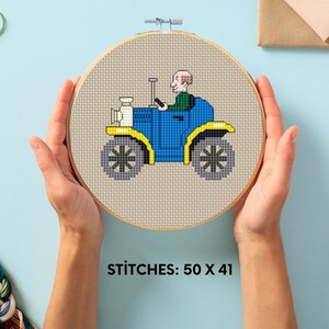 Puede incluir: Un patrón de punto de cruz de un coche azul con un volante amarillo y una persona conduciendo. El patrón está sobre un fondo beige y tiene el texto "STITCHES: 50 X 41".