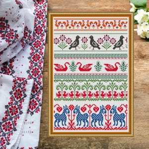 Puede incluir: Un muestrario de punto de cruz enmarcado con un diseño de arte popular. El bordado presenta filas de pájaros, cisnes y caballos en rojo, negro, verde y azul sobre un fondo blanco. El marco es de un cálido marrón dorado.
