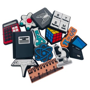 May include: A collection of colorful science-themed charms, including a calculator, notebook, atom, flask, Rubik's cube, laptop, ruler, and microscope. The charms are in various colors, such as red, blue, black, and orange.
