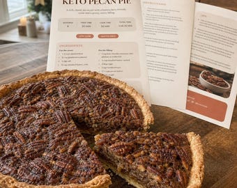 Op de afbeelding: Een ronde keto pecannotentaart met een goudbruine korst en een dichte, nootachtige vulling met hele pecannoten. Achter de taart ligt een geprinte receptenkaart met de titel CraveLab Keto Pecan Pie, met ingrediënten en instructies.