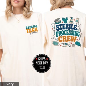 May include: Ivory-colored t-shirt with the text "STERILE TECH Sophia" on the front. The back features the words "STERILE PROCESSING CREW" with medical-themed illustrations in teal, orange, and blue.