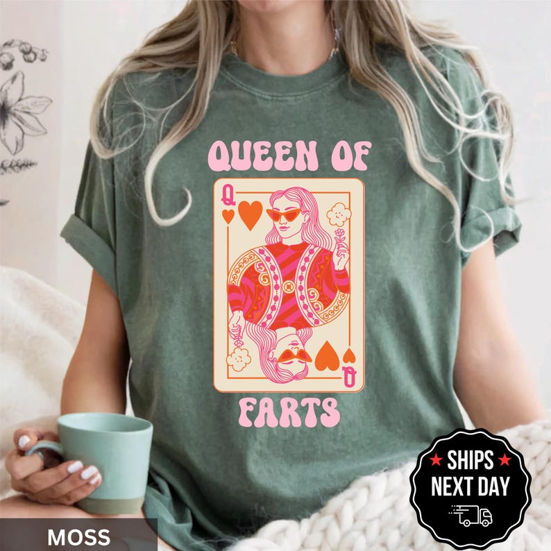 A woman wearing a green t-shirt with a graphic design of a woman with sunglasses and the text "Queen of Farts" printed on it.