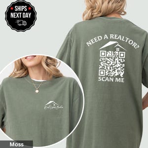 May include: Moss green t-shirt with a white house logo and "Real Estate Broker" text on the front. The back features the text "NEED A REALTOR?" above a QR code and "SCAN ME" below. A round black sticker with white text is in the upper left corner.