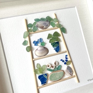 May include: A framed artwork featuring a ladder-shaped shelf with various potted plants, all crafted from sea glass and shells. The plants are in blue and green pots, with green foliage and blue flowers. The artwork is set against a white background.