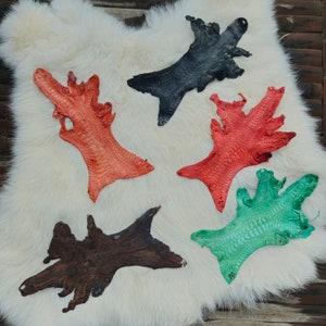 May include: Five different colored leather pieces with a textured pattern. The pieces are arranged on a white fur background. The colors are black, orange, red, green, and brown.