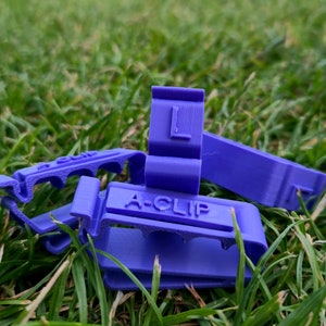 May include: Purple plastic clips with the text "A-CLIP" and "L" printed on them. The clips are designed to hold items together.