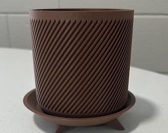 May include: A brown plastic planter with a textured, diagonal pattern. The planter has a matching saucer with three legs.